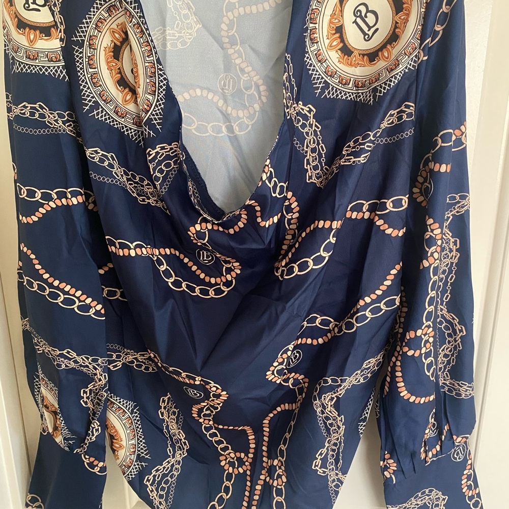 Brand new, navy blue women’s blouse with chain drawings throughout.